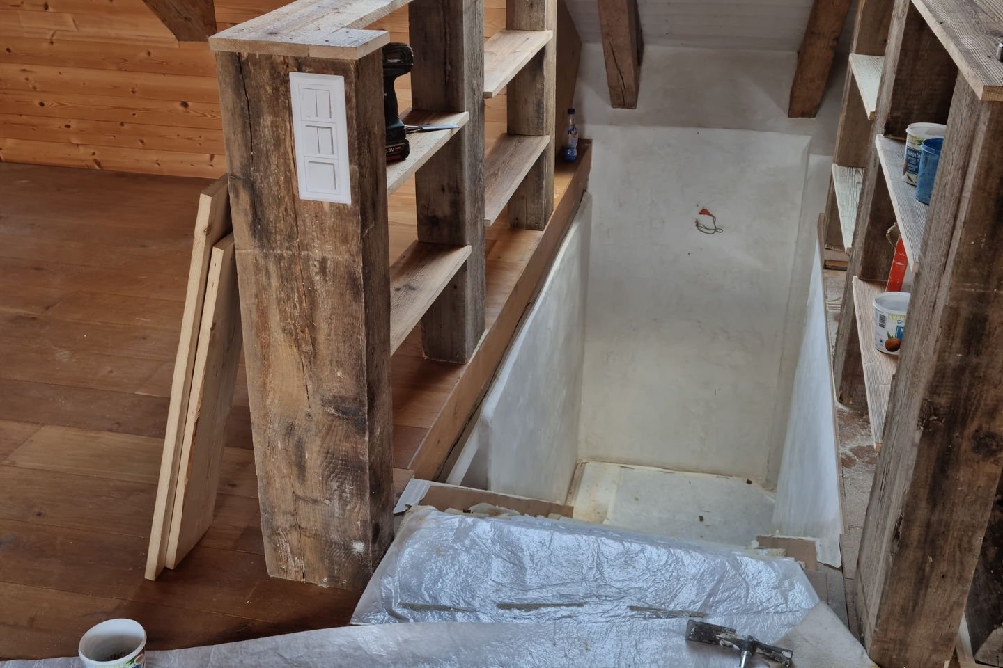 Poteaux en vieux bois posés en bord de plancher, sous une charpente ancienne éclairée par un velux