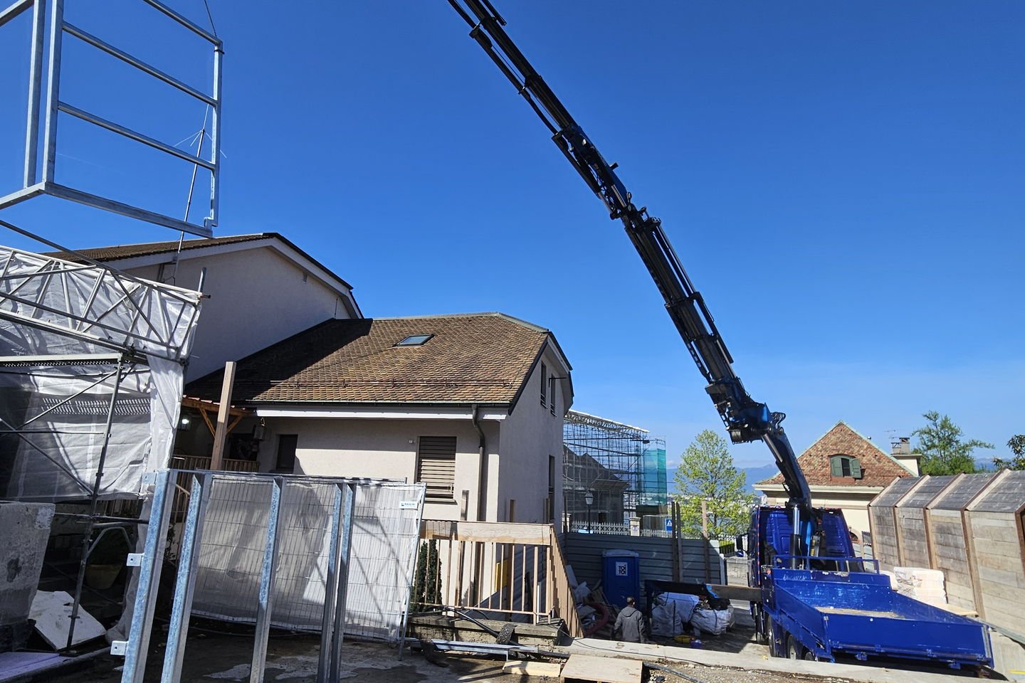 Élément métallique suspendu à l’élingue de la grue, au-dessus d’une dalle en construction