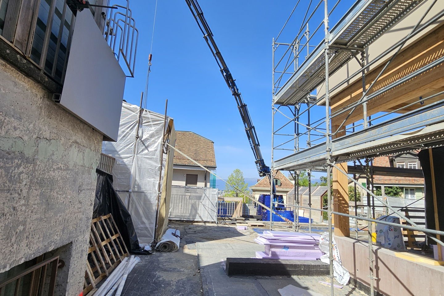 Passage étroit entre deux bâtiments avec échafaudage, la flèche de la grue au-dessus