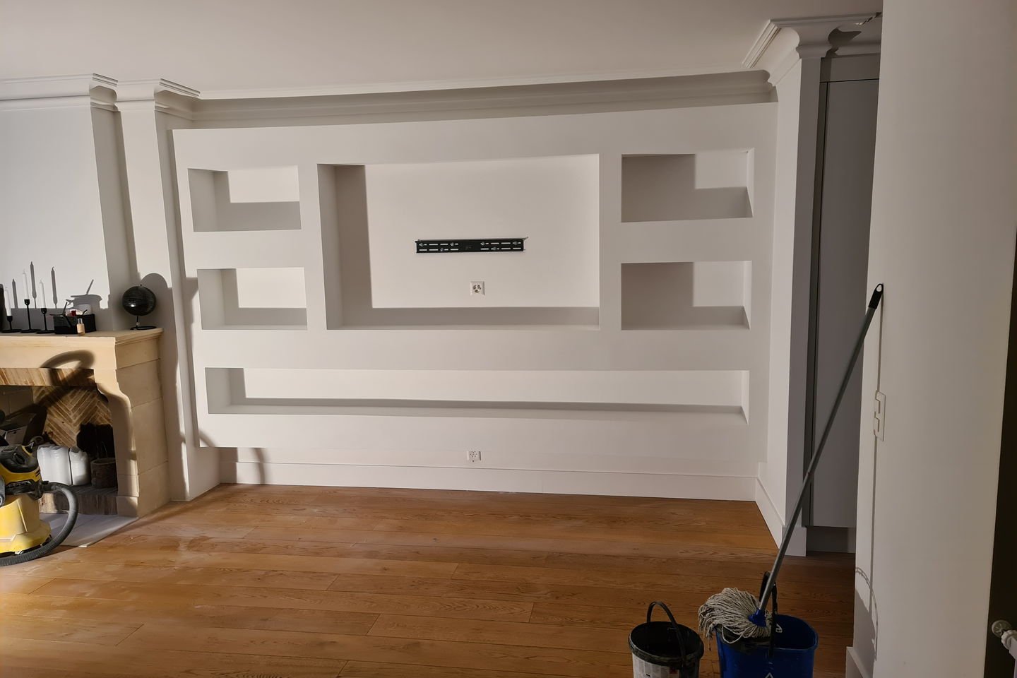 Paroi TV en plâtrerie sur mesure : niches et étagères sculptées dans le mur, peinture blanche