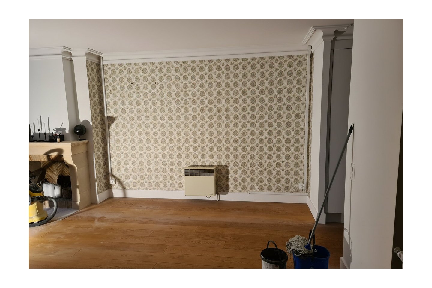 Séjour ancien reconstitué : mur en papier peint à motifs et vieux convecteur, sans niches