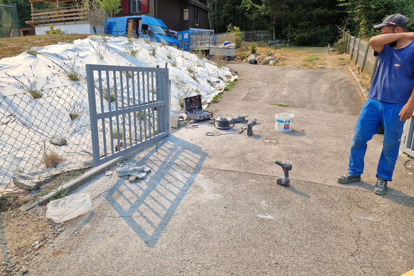 Vantail de portail posé à plat au sol pendant le montage, avec les outils autour