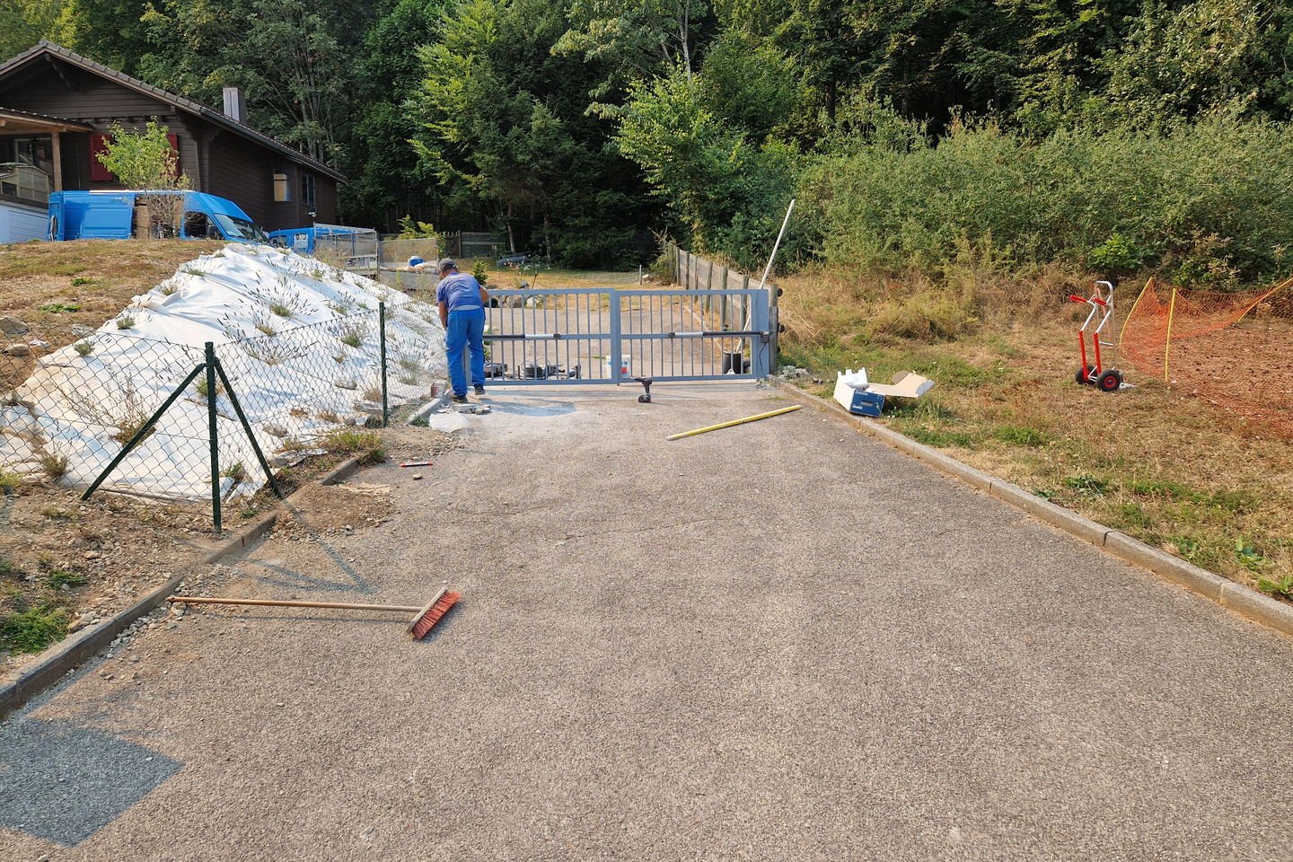 Accès en béton avant travaux, ouvert sur la route, avec une clôture provisoire