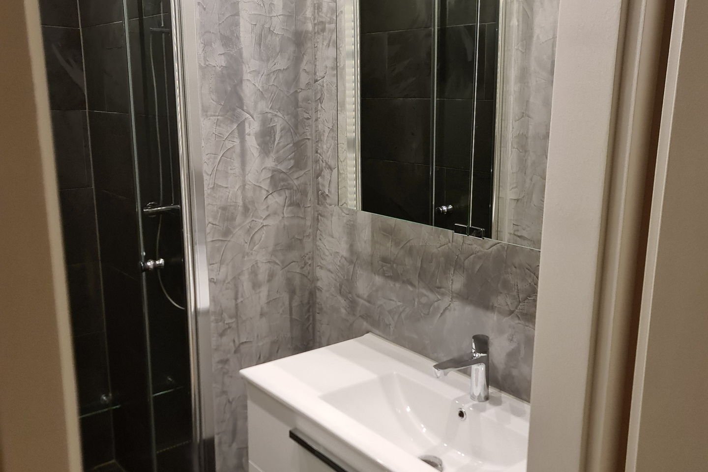 Salle d’eau anthracite avec meuble vasque blanc suspendu, grand miroir et douche vitrée au fond