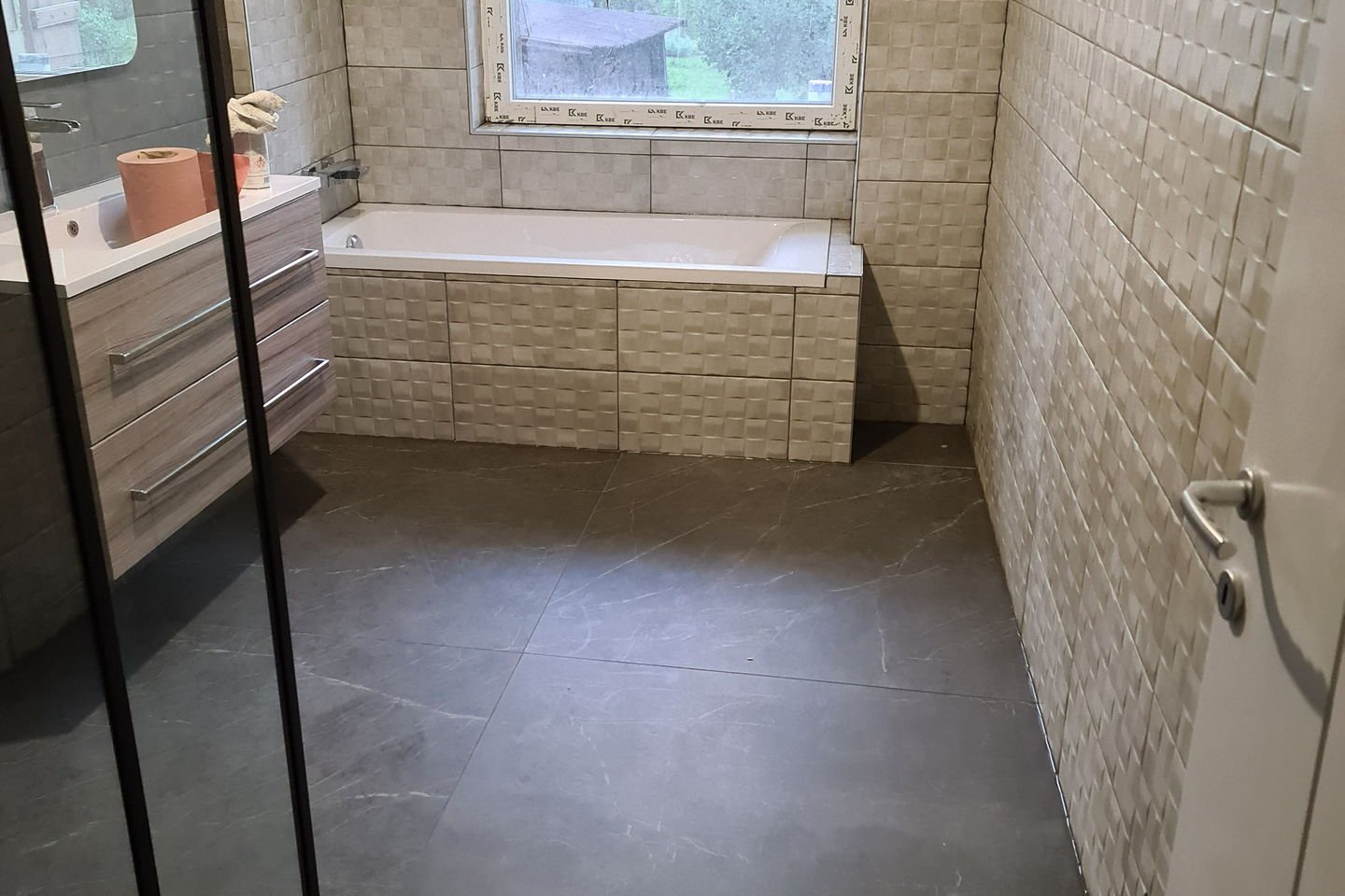 Ancienne salle de bains carrelée en beige clair du sol au plafond, avec baignoire encastrée