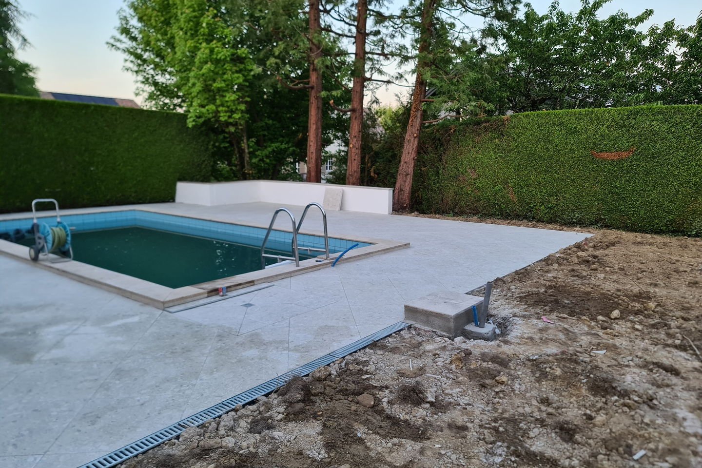 Terrasse de piscine refaite : grandes dalles de pierre claire posées à plat, joints nets, margelle neuve