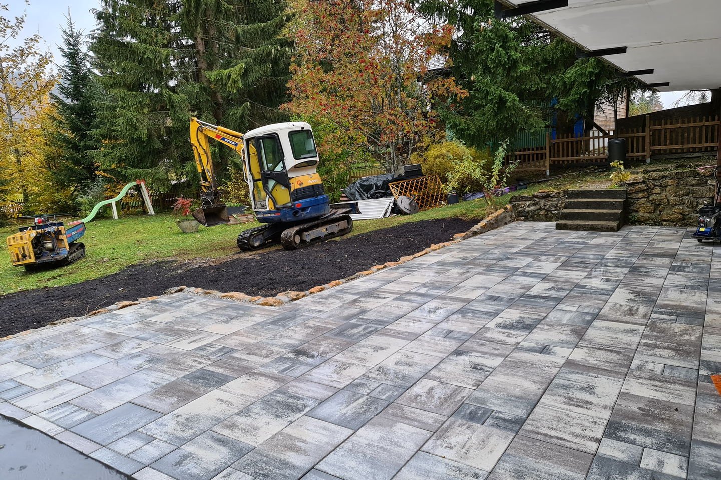 Mini-pelle sur chenilles en bordure de la terrasse en cours de finition